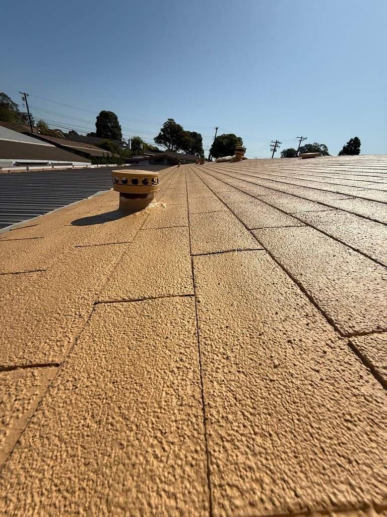 Close view along a roof slope finished in tan Roof Coat, including the vent