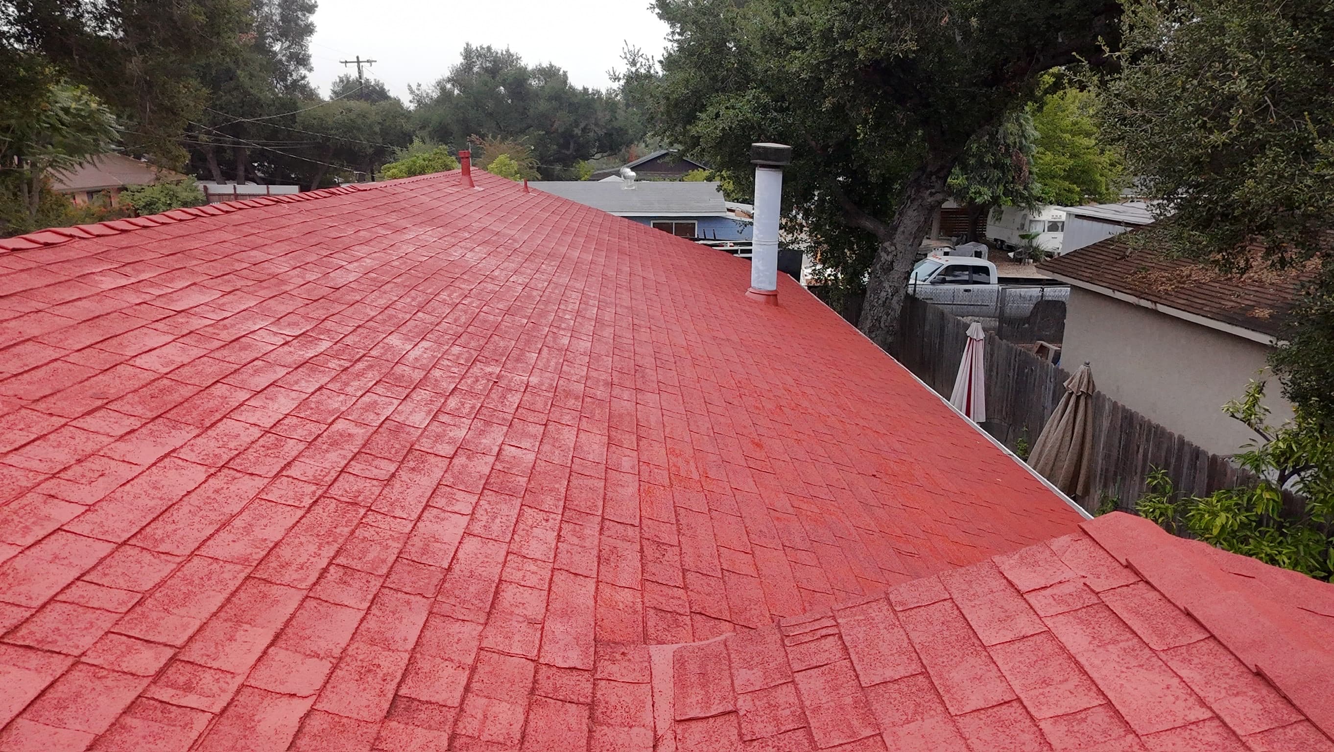 View along the ridge of a finished terracotta roof, every shingle butt line still reading through the coating