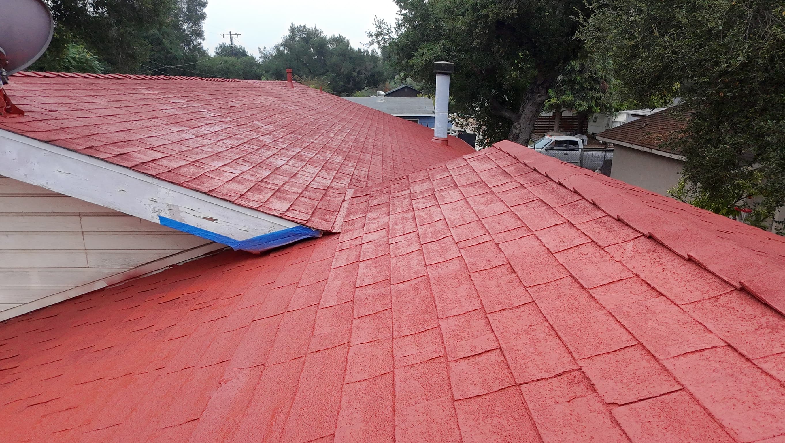 The coated roof meeting white trim, blue masking tape still on the fascia where the film stops