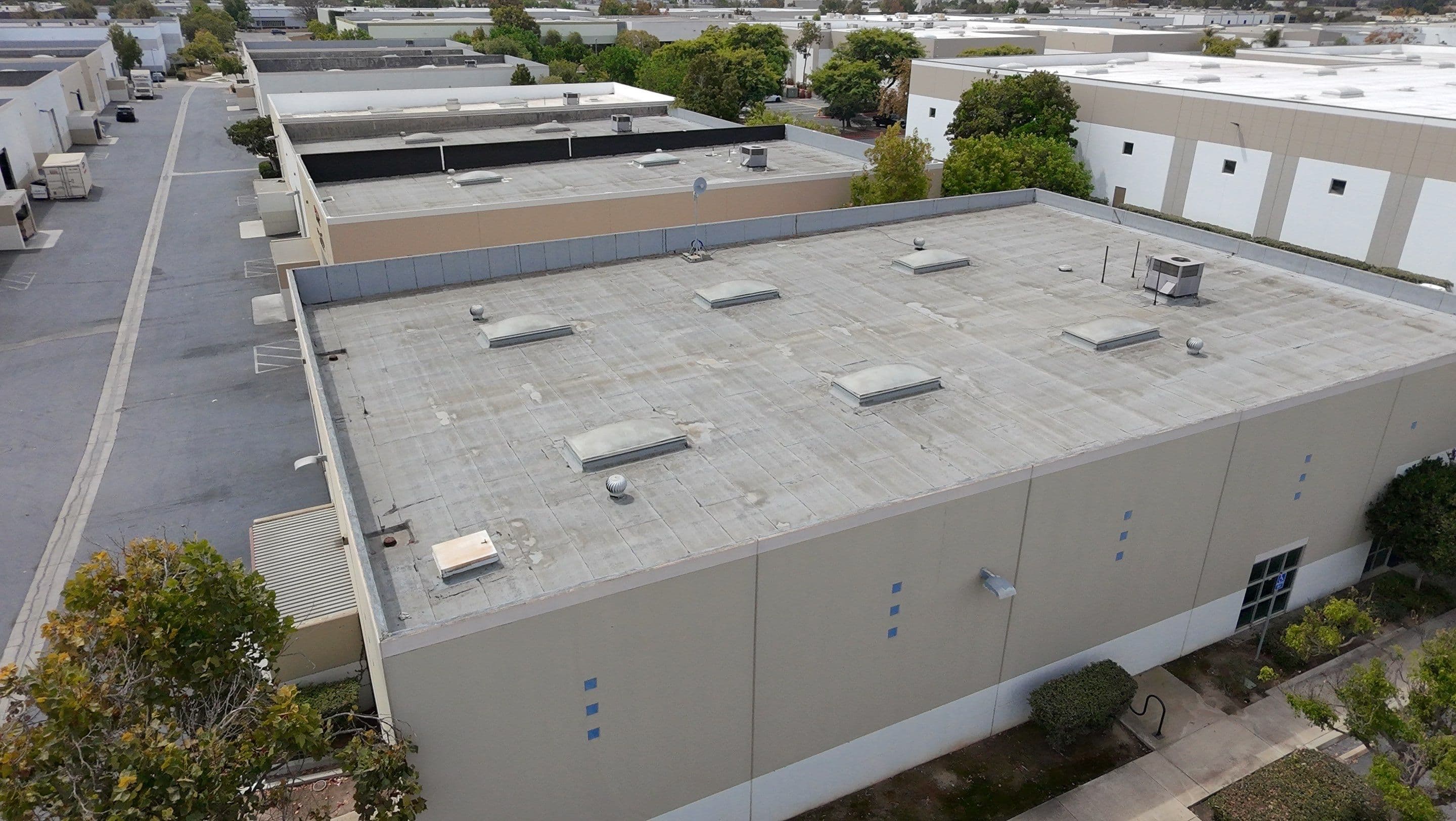 Overhead of a worn low-slope commercial roof in Oxnard before any coating.