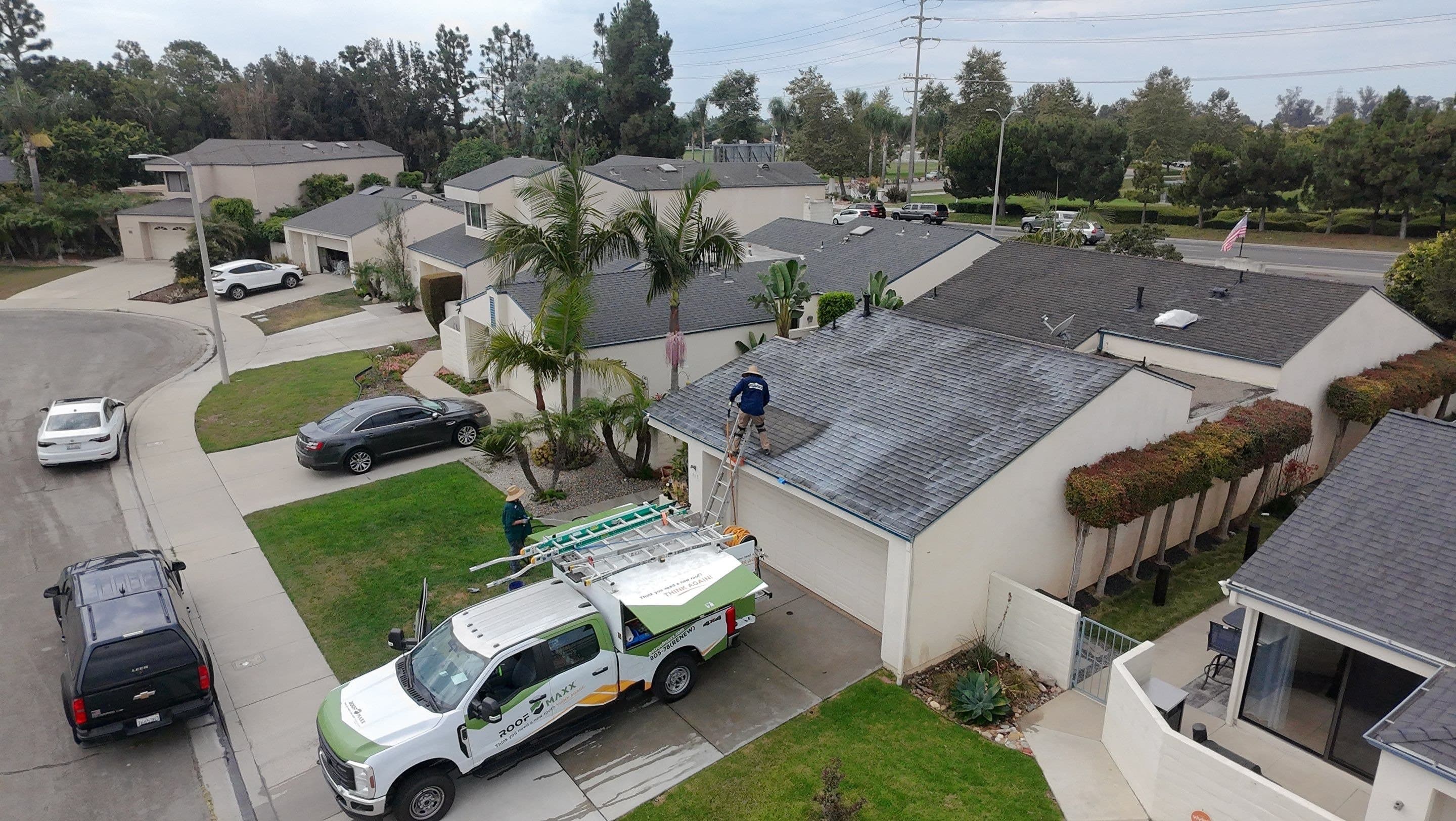 A work truck parked on a Ventura street with a ladder up to the roof.