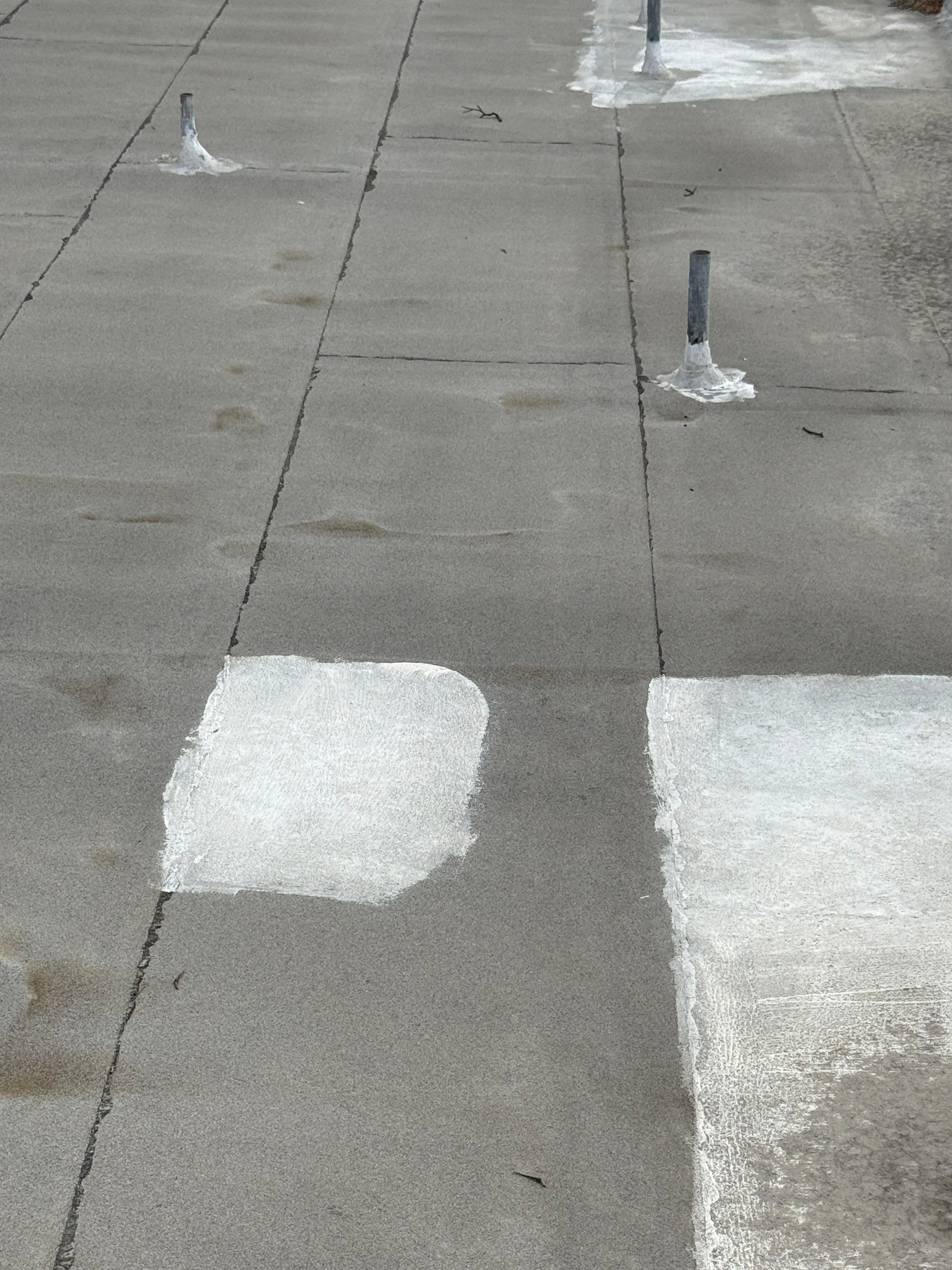 Overlapping patches of different roofing materials covering the flat roof field.