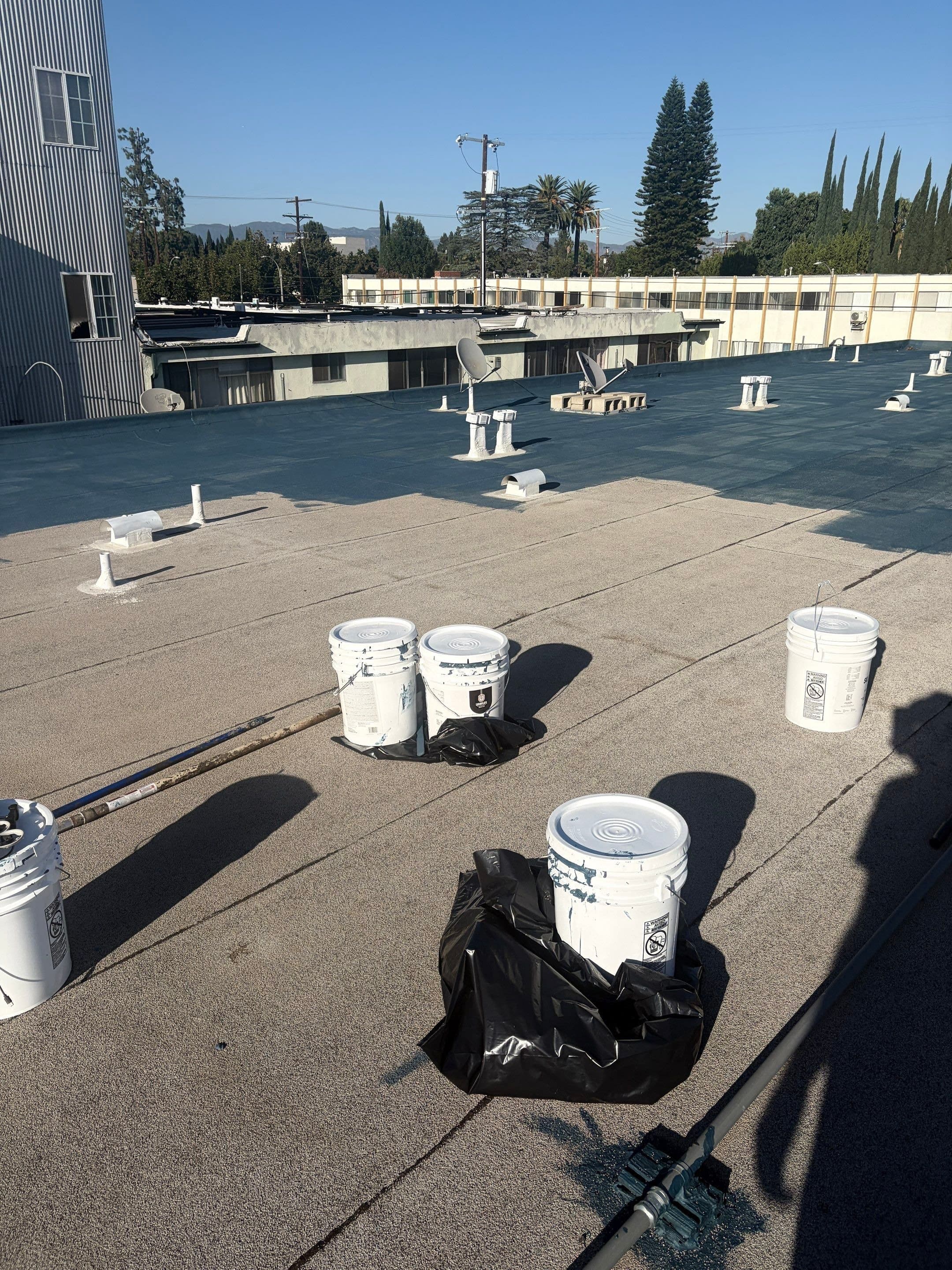 Coating pails and supplies staged on the flat roof before the work.