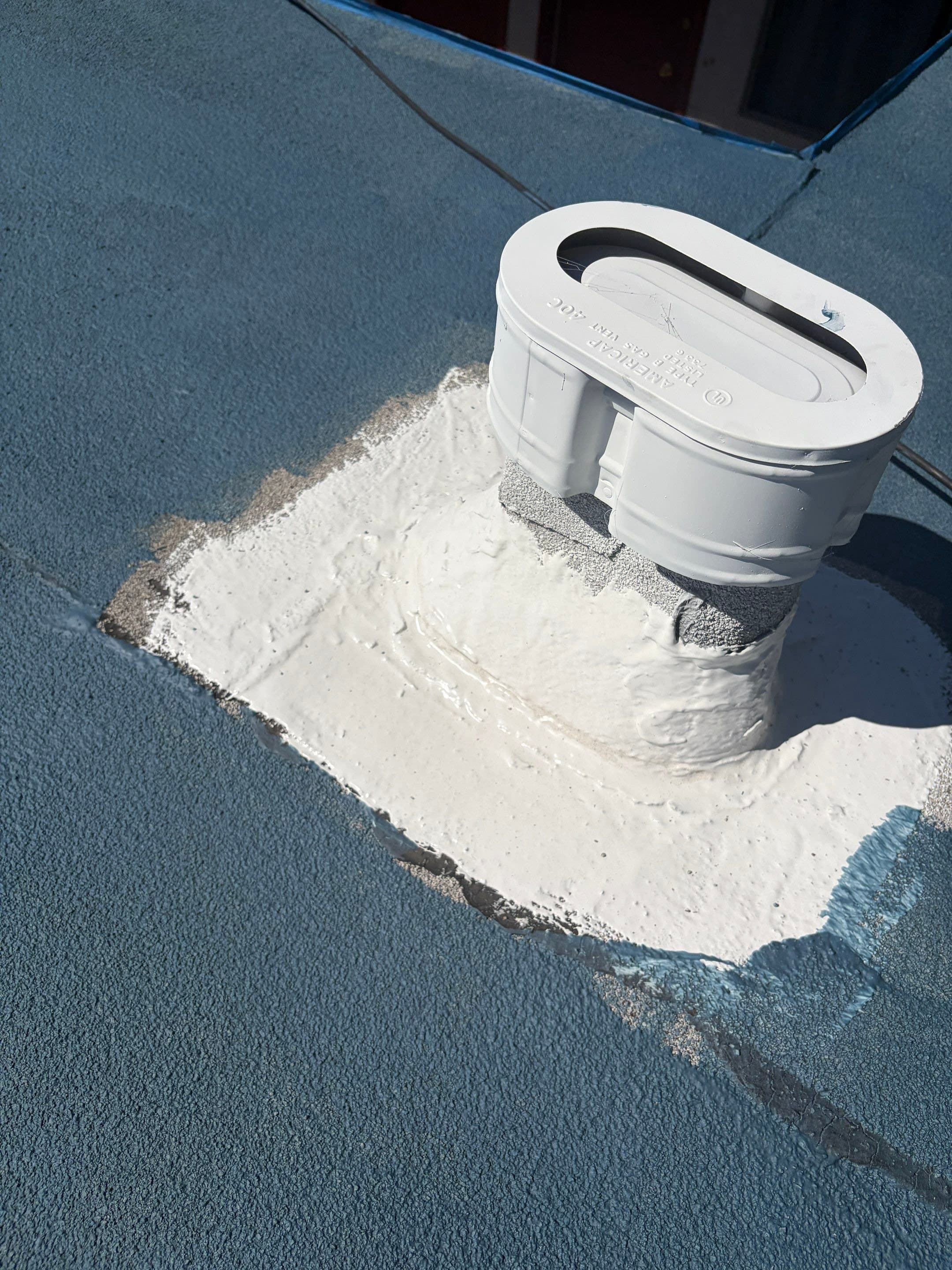 A vent curb wrapped in white reinforcement fabric before the field is coated.
