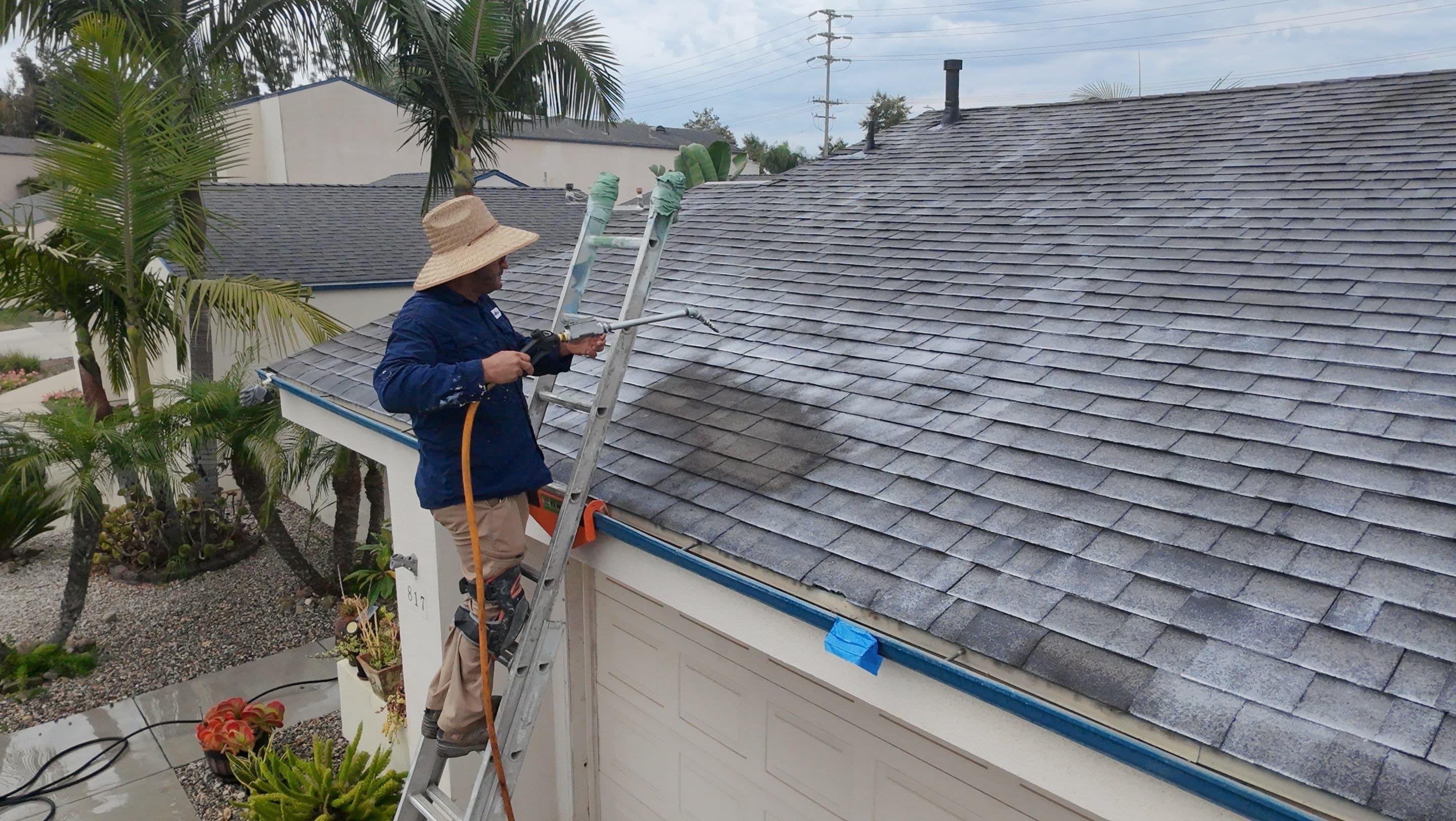 A technician on a ladder spraying Roof Maxx along the eave of a Ventura roof.