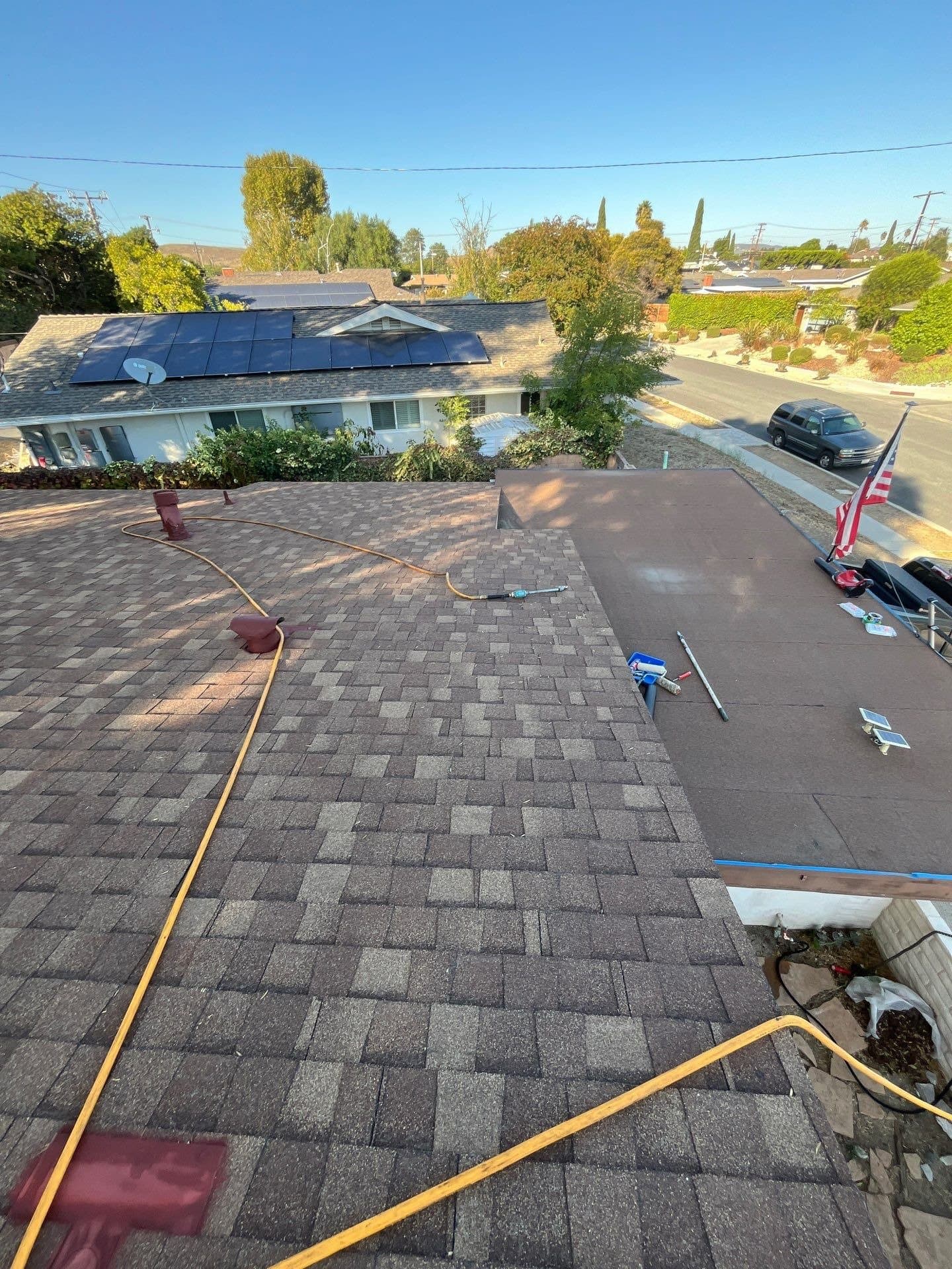 A roller spreading white coating across the flat deck of a Thousand Oaks roof.